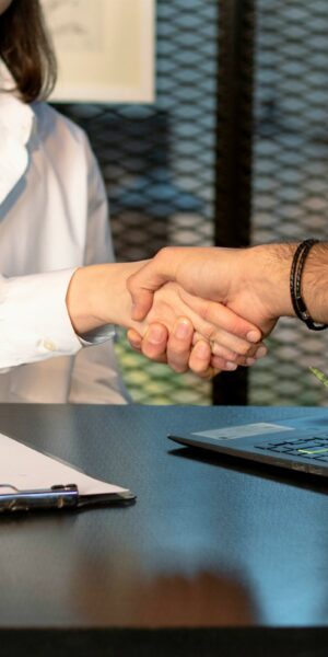 a man and a woman shaking hands in front of a laptop